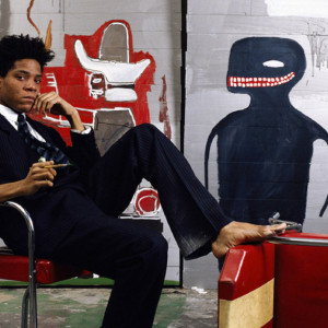 IMAGE PROVIDED BY BROOKLYN MUSEUM NO SALES NO LOCATION PROVIDED **FILE** In this 1985 image provided by the Brooklyn Museum, the artist Jean-Michel Basquiat is shown surrounded by his work. An exhibit of his work opened Friday, March 11, 2005, at the Brooklyn Museum and runs through June 5, before traveling to Los Angeles and Houston. (AP Photo/Brooklyn Museum, Lizzy Himmel, File)