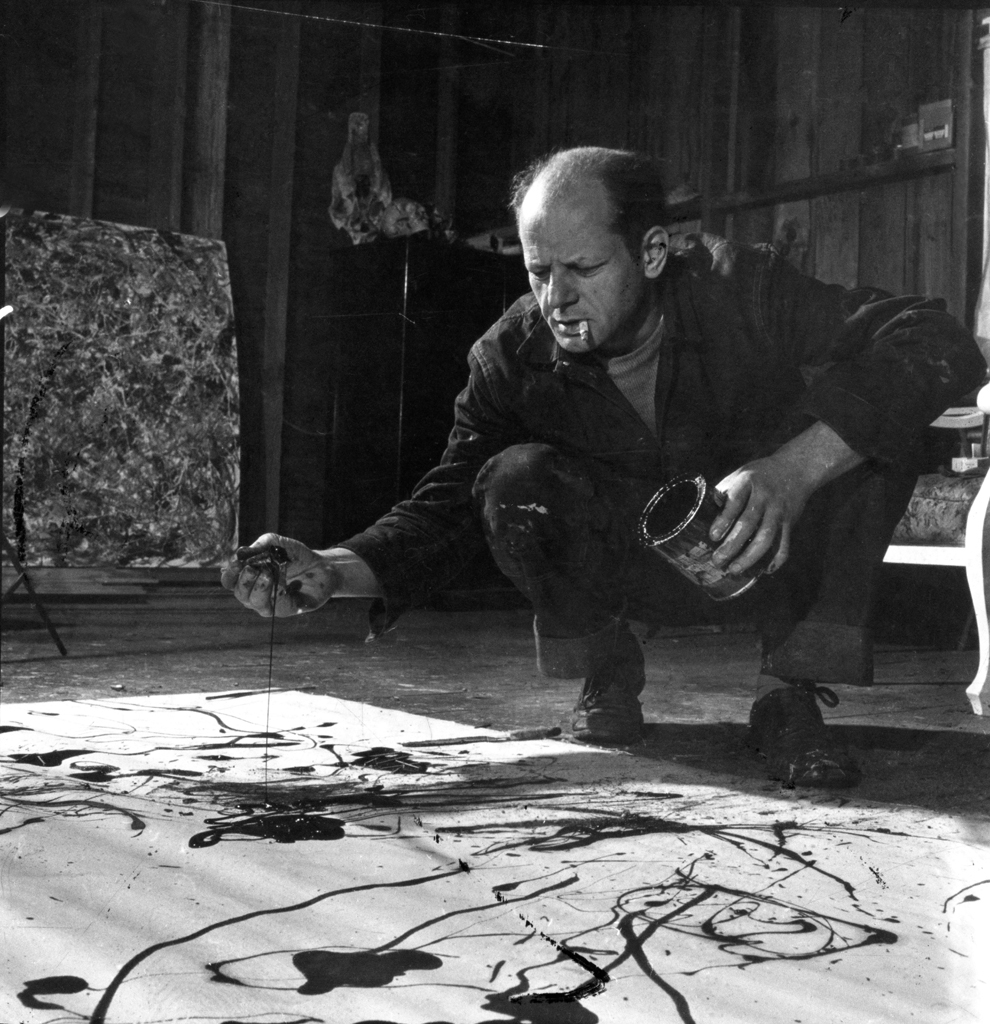 pollock drips paint onto the canvas, his signature style