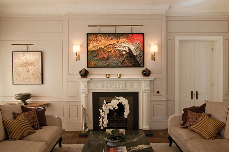 Textured modern abstract lit above a mantel in a traditional home